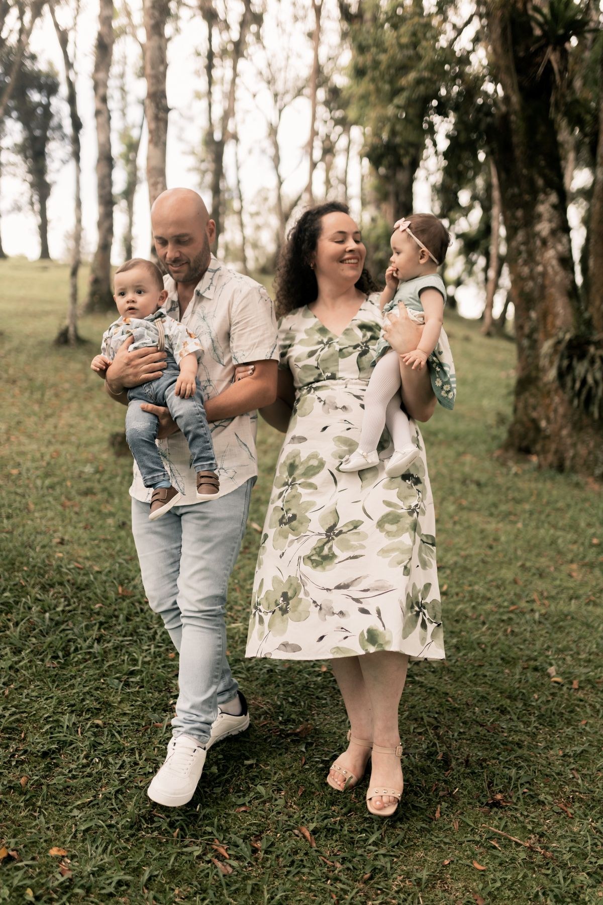 Parents carrying their two young children during a walk in the park